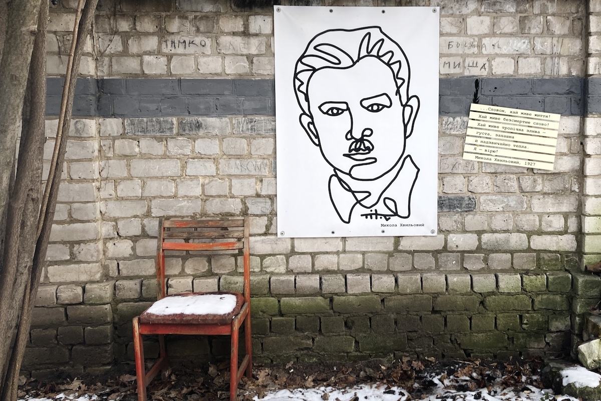 Porträt und Zitat von Mykola Chwyljowyj aus „Wstupna Novela“ (1927) an der Gartenmauer des Charkiwer Literaturmuseums: „Mit einem Wort, es lebe das Leben! Es lebe das unsterbliche Wort! Es lebe der tropische Regen – dicht, duftend und unglaublich warm. Ich glaube daran!“ / Foto © Peggy Lohse/dekoder, 02/2025